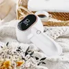 A white lint remover with a digital display sits on a textured white blanket, next to a small cup of coffee and some dried flowers. Produktbild-Vorschau