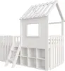 A white wooden house-shaped bed with a sloped roof, a window, and a fence-like railing, shown from a side-front angle. A ladder is attached to the left side, leading up to the bed. The lower section of the bed has open cubbies for storage. Náhľad obrázku produktu