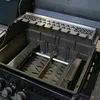 Close-up view of the inside of a grill, showing the burner cover and other internal components. Voir les images du produit