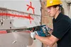 A construction worker is using a Bosch hammer drill to break a wall. Produktbild-Vorschau