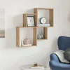 A set of wooden cube shelves mounted on a white wall, decorated with books, vases, and a framed picture. A blue armchair and a small round table are visible in the foreground. Produktbild-Vorschau