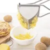 A potato ricer is being used to press potatoes into a bowl, with cooked potato pancakes and raw potatoes visible. Anteprima dell’immagine prodotto