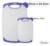 Two white cutting boards with purple trim and handles are shown side-by-side on a white background. Text indicating dimensions and a brand logo are present. Anteprima dell’immagine prodotto