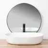 A white oval vessel sink with a black faucet in front of a large round mirror. Anteprima dell’immagine prodotto