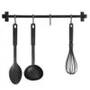 A black metal kitchen utensil rack with a ladle, a spoon, and a whisk hanging from it. Anteprima dell’immagine prodotto