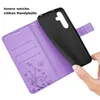 A hand is holding a black phone case over an open purple wallet case with card slots and a floral design. Produktbild-Vorschau