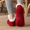 Rote gestrickte Hausschuhe-Socken mit weißem Fleecefutter und Anti-Rutsch-Noppen auf der Sohle, getragen von einer Person auf einem Teppich Náhľad obrázku produktu