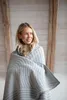 A woman wrapped in a striped blanket indoors. Produktbild-Vorschau