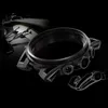 A watch case and a sketch of a watch component are shown against a dark background, with a blurred image of a race car in the upper left corner. Produktbild-Vorschau