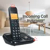 A cordless phone on its charging base, with a blurred background of a modern living/dining area. Náhled obrázku produktu