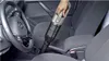 A person is using a handheld vacuum cleaner inside a car. Produktbild-Vorschau