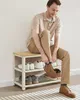A man tying his shoe while sitting on a shoe rack. Produktbild-Vorschau