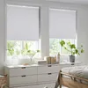 A bedroom scene with two windows covered by white pleated blinds, a dresser with drawers, and a bed partially visible. Produktbild-Vorschau
