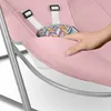 A close-up of a pink baby bouncer with a hand gently pressing on the fabric. Produktbild-Vorschau