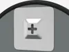A close-up of a white square fixture with a cross-shaped indentation, set against a gray background with a black curved edge at the top. Náhled obrázku produktu