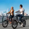 A couple riding electric bikes along a waterfront with a city skyline in the background. Anteprima dell’immagine prodotto