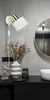 A bathroom vanity with a wall lamp, vase of dried flowers, candle, and a decorative bust. Produktbild-Vorschau