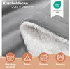 A close-up of a gray and white sherpa blanket, with icons and text indicating its features and uses. Náhled obrázku produktu