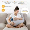 A woman is breastfeeding a baby while sitting on a couch, using a large nursing pillow. Produktbild-Vorschau