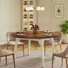 A dining room scene with a round wooden table set for a meal, surrounded by chairs. A wine cabinet and a plant are visible in the background. Náhľad obrázku produktu