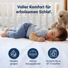 A baby sleeping on a mattress next to a teddy bear, with feature icons at the bottom. Produktbild-Vorschau