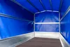 Interior view of an empty trailer with blue tarpaulin sides and roof, and a gray metal frame. The floor is dark brown. Podgląd zdjęcia produktu