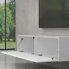 A white TV lowboard with two open doors is mounted on a concrete wall, with a large window showing trees and greenery in the background. Produktbild-Vorschau