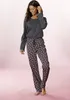 A woman modeling a two-piece pajama set against a pink background. Produktbild-Vorschau