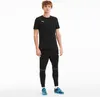 A man wearing a black Puma t-shirt and black Puma pants, standing against a white background. Anteprima dell’immagine prodotto