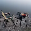 A folding chair and table set up by a body of water, with fruit on the table. Produktbild-Vorschau