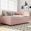 A pink upholstered daybed with a pull-out trundle bed is set up in a bright room with a large window and artwork on the wall. Náhľad obrázku produktu