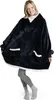 A woman wearing a dark blue hooded blanket with white trim and pockets, standing against a white background. Produktbild-Vorschau