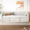 A beige upholstered daybed with storage drawers is shown in a well-lit room with a painting on the wall and a plant in the corner. Voir les images du produit