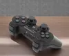 A black wireless gamepad is placed on a wooden surface with a gray textured background. Voir les images du produit