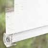Close-up of a white roller blind with a clear plastic bracket. Produktbild-Vorschau