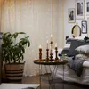 A cozy living room scene with a string of fairy lights, a plant, and decorative candles. Produktbild-Vorschau