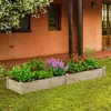 A raised garden bed filled with various plants, including vegetables and flowers, placed on a grassy lawn in front of a building. Podgląd zdjęcia produktu