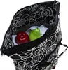 A close-up view of the inside of a black and white floral patterned trolley bag, containing a red apple and a green pear. Podgląd zdjęcia produktu