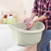 A person is washing clothes in a basin in a bathroom. Produktbild-Vorschau