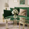 A modern living room with a green velvet sofa and gold coffee tables. Produktbild-Vorschau