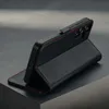 A black leather phone case with red stitching is displayed on a dark, textured surface. Anteprima dell’immagine prodotto