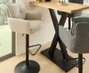 Two bar stools are shown next to a wooden bar table in a well-lit room with a window overlooking a garden. Produktbild-Vorschau