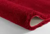 A close-up view of the edge of a red rug, showing its texture and fringed edge. Produktbild-Vorschau