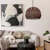 A dog is lying on a sofa next to a coffee table with a plant and a pendant lamp hanging above. Anteprima dell’immagine prodotto