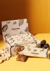 A box of cashew raw bars with some cashews and dates scattered around. Produktbild-Vorschau