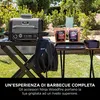 A Ninja Woodfire grill and accessories are set up on a table outdoors in a grassy area with trees in the background. Anteprima dell’immagine prodotto
