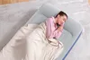 A woman is sleeping on an inflatable mattress on a rug. Produktbild-Vorschau