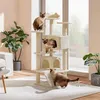 Three Siamese cats interact with a multi-level cat tree in a well-lit room with plants. Podgląd zdjęcia produktu
