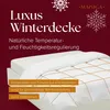A close-up marketing image of a white winter duvet with a gold grid pattern, set against a dark red background with snowflake graphics and text. Produktbild-Vorschau