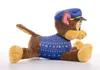A plush toy dog wearing a blue hat and a blue sweater with a festive pattern, lying on its side against a white background. Produktbild-Vorschau